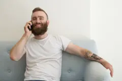 Bearded man sitting on a sofa chatting on the phone