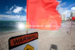 Red flag blowing in the wind on the beach