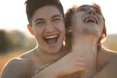 Two laughing gay men in a loving embrace