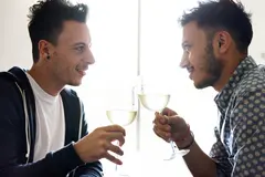 Two gay men clinking wine glasses