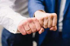Two men's clenched hands aside showing their wedding rings