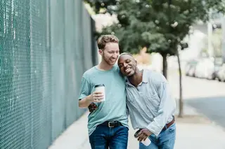 Happy gay men couple walking along the street