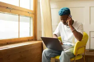 Man using his phone while looking at a laptop